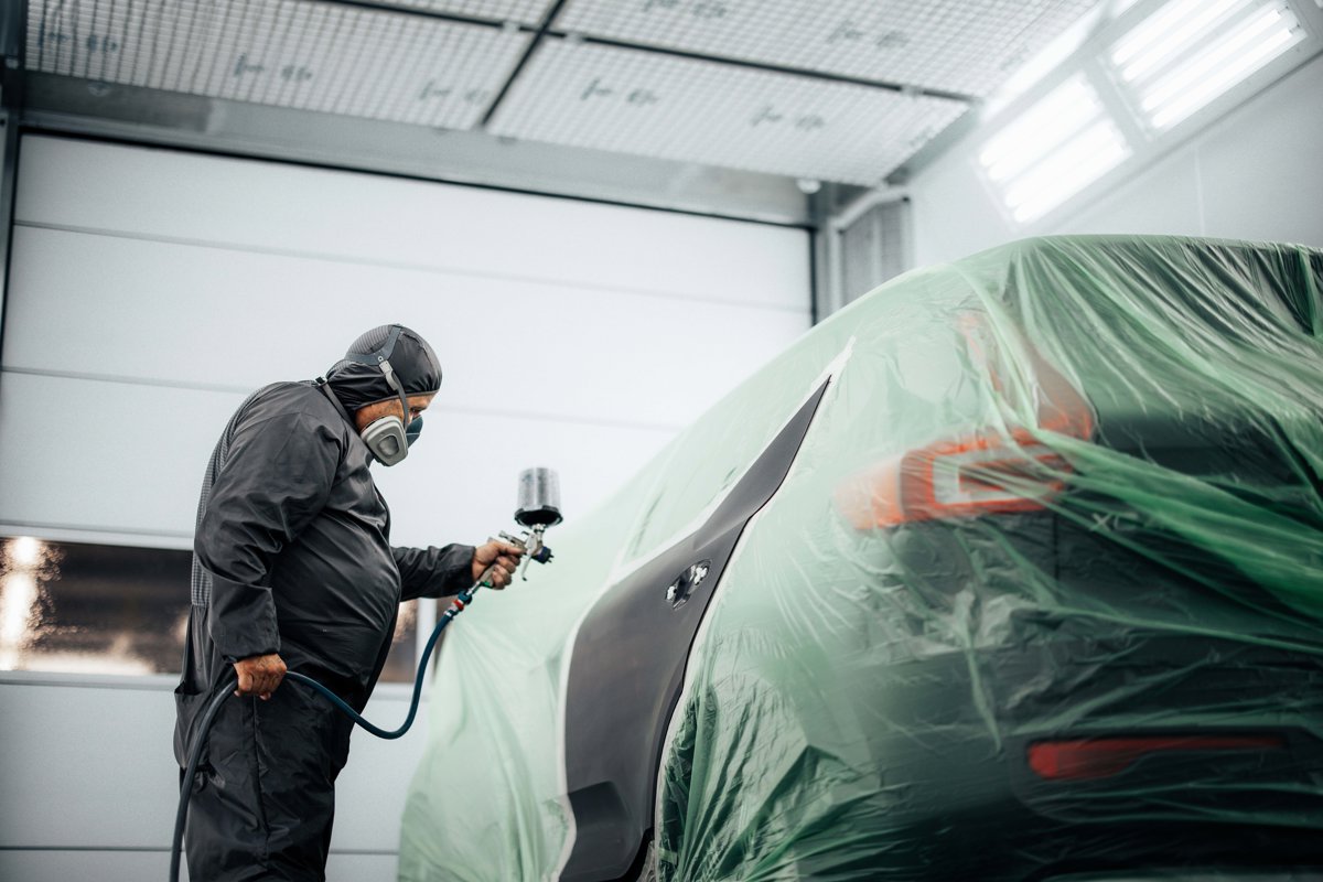 Een autospuiter van Autoschade De Kade aan het werk